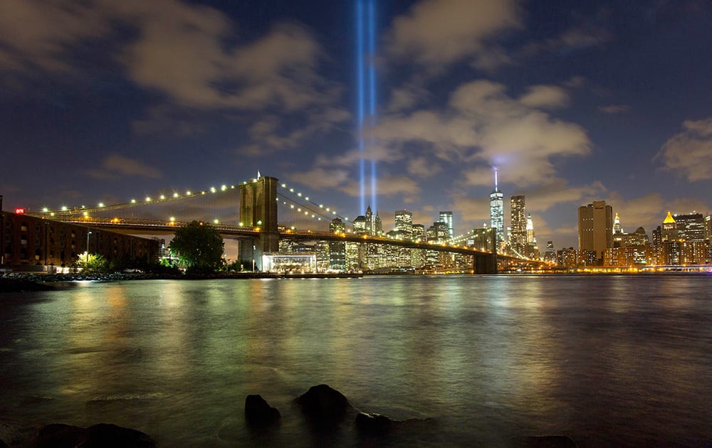 The Tribute in Light rises behind the Brooklyn Bridge and buildings adjacent to the World Trade Center complex, in New York. The tribute, an art installation of 88 searchlights aiming skyward in two columns, is a remembrance of the Sept. 11, 2001, attacks.