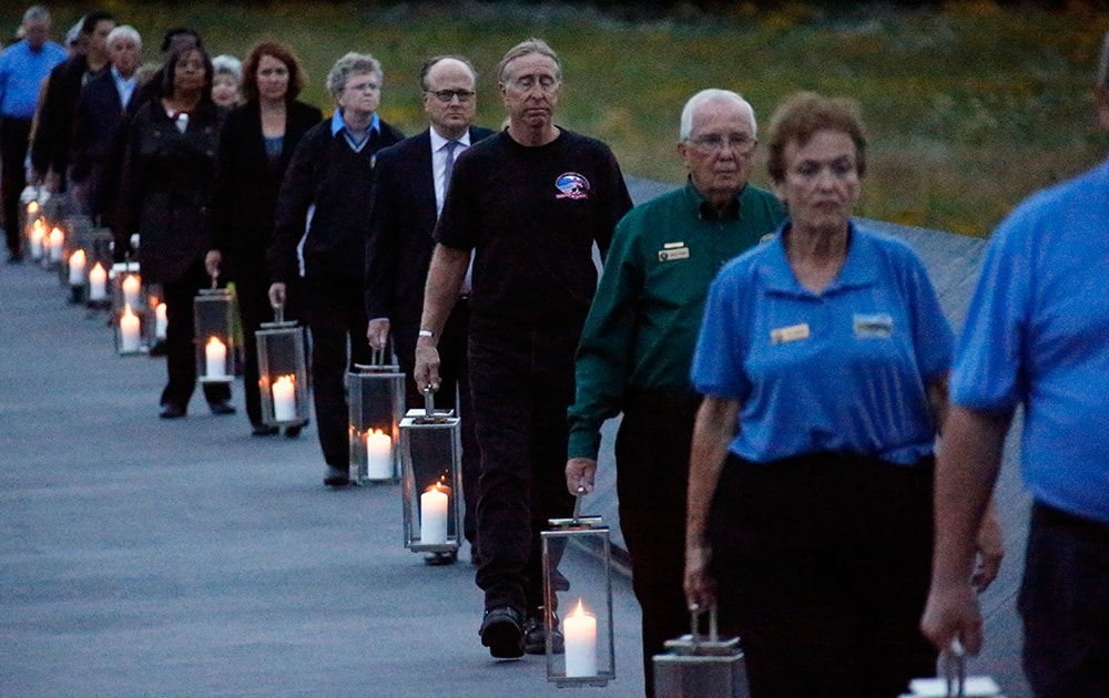 Candles in memory of the 40 passengers and crew of Flight 93, are carried to the Wall of Names at the Flight 93 National Memorial in Shanksville, Pa.. Thursday marks the 13th anniversary of the Sept. 11 terror attacks.