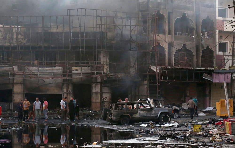 People inspect the site of a double car bomb attack at a busy market in Ghadeer district in southeastern Baghdad, Iraq. A series of attacks, mainly car bombings targeting security forces and markets, killed and wounded dozens of people Wednesday in Iraq’s capital, authorities said. 