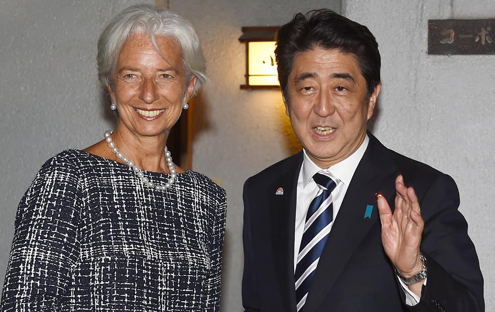 International Monetary Fund (IMF) Managing Director Christine Lagarde, left, and Japanese Prime Minister Shinzo Abe pose for photos at an entrance of the sushi restaurant Kozasa in Tokyo.