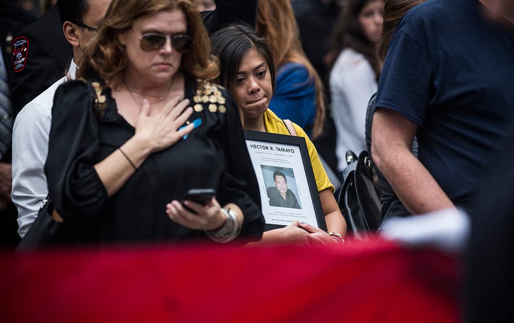 Women mourn as officials carry an American flag past them at the beginning of the memorial observances on the 13th anniversary of the Sept. 11 terror attacks on the World Trade Center in New York.