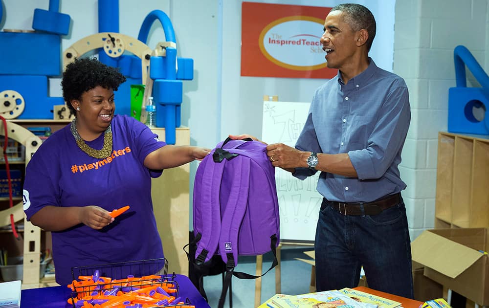 President Barack Obama stuffs backpacks that will be donated to homeless children as he participates in a service project at the Inspired Teaching School to mark the 13th anniversary of the 9/11 attacks.