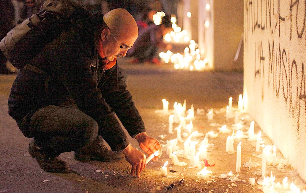 A man lights a candle in the front of the National Stadium during a candlelight vigil marking the 41st anniversary of the military coup that ousted the late President Salvador Allende, in Santiago, Chile.