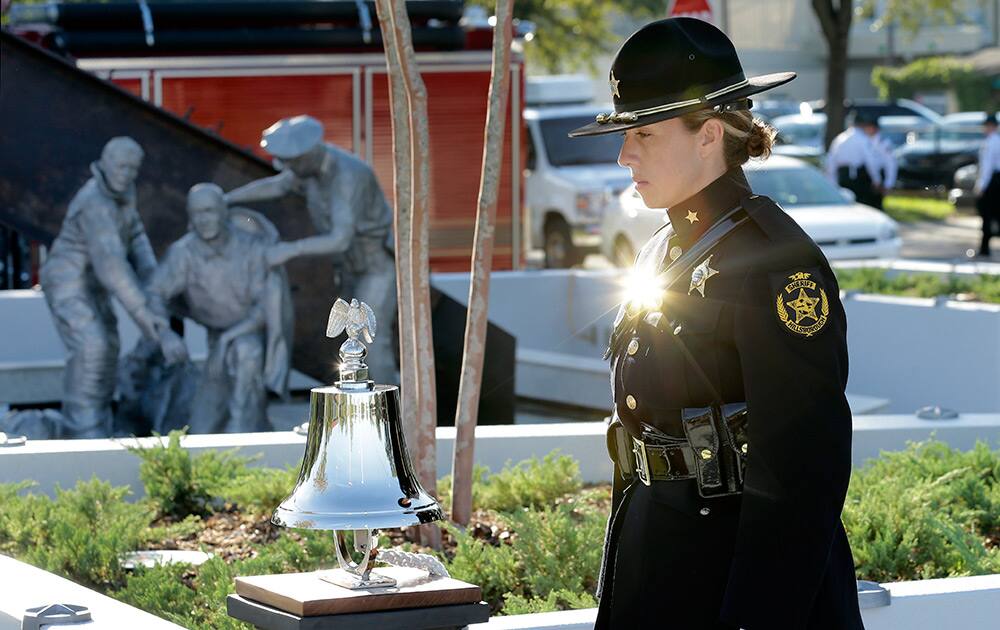 Hillsborough County Sheriff's Office honor guard member Stacie Woods, the sun reflecting off of her name tag, stands at attention near a 9/11 Fallen Heroes Memorial as it was unveiled, in Tampa, Fla.