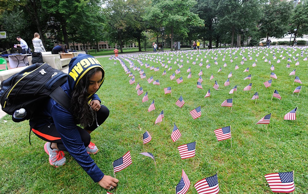 Lauren Marinez places one of 2977 American flag in the grass at the University of Michigan Thursday, Sept. 11, 2014, in Ann Arbor, Mich., to honor the victims of the Sept. 11 terrorist attacks.