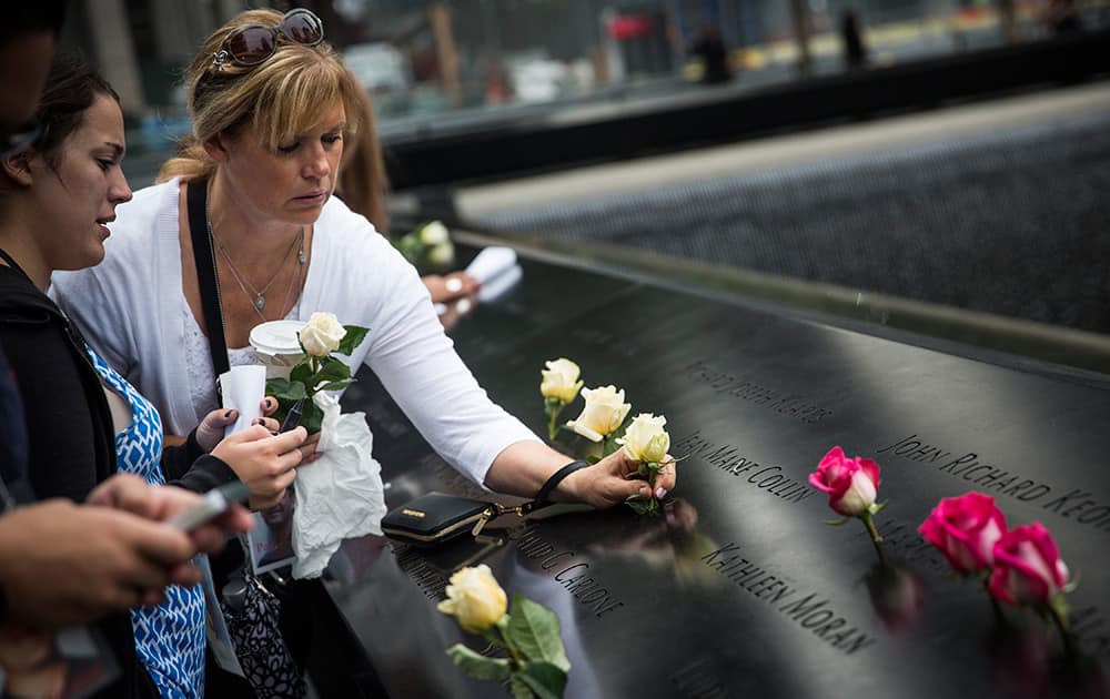 A woman places flowers on the name of a loved one during memorial observances on the 13th anniversary of the Sept. 11 terror attacks on the World Trade Center in New York.