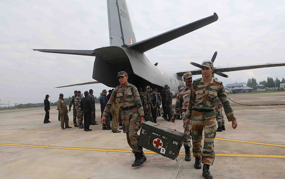 Indian army soldiers carry medical supplies for flood victims as they arrive an air force base in Srinagar.