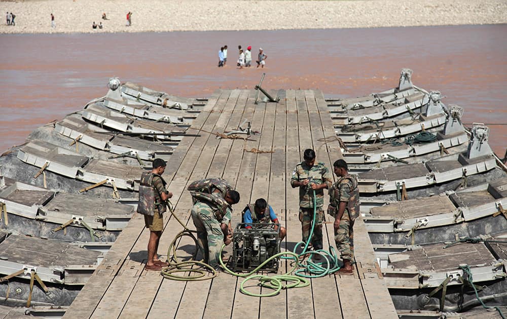 Indian army soldiers build a temporary bridge across the Tawi River after the existing bridge was damaged in the floods on the outskirts of Jammu.