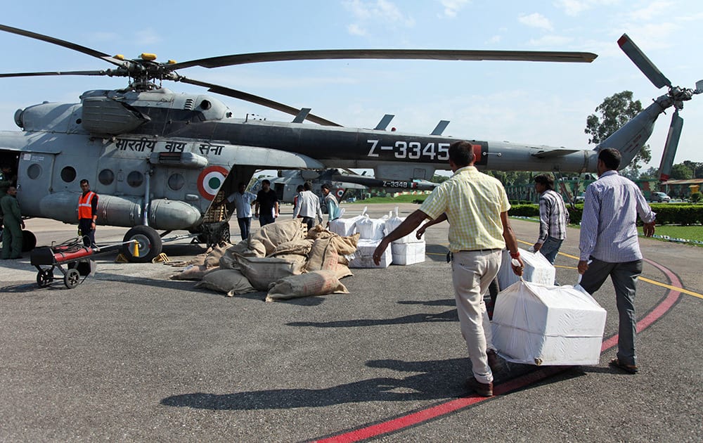 Relief workers load material for flood-affected victims in Jammu.