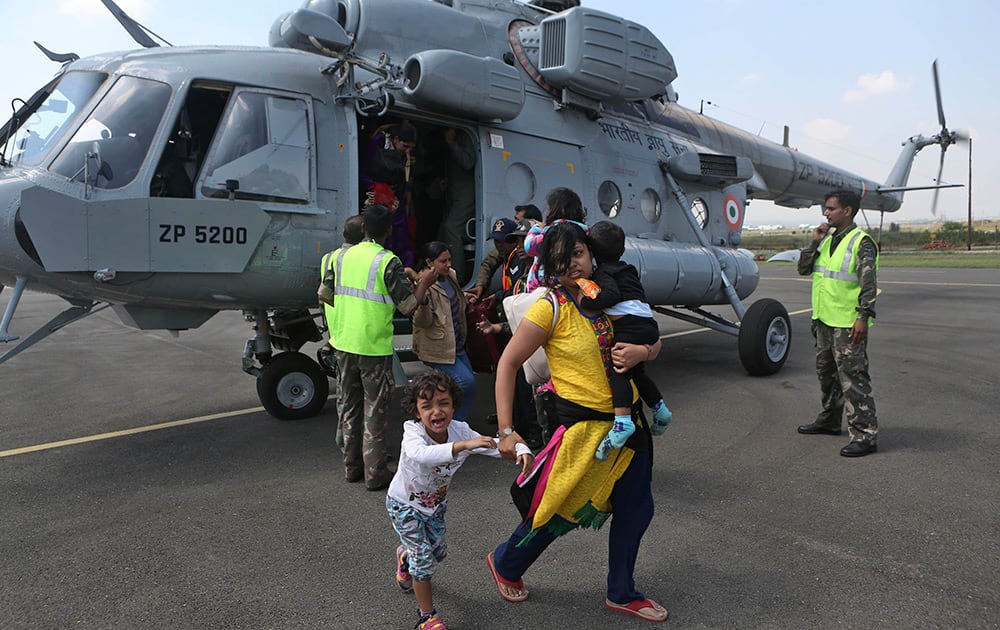 Tourists rescued from flooded areas arrive with their children at an air force base in Srinagar.