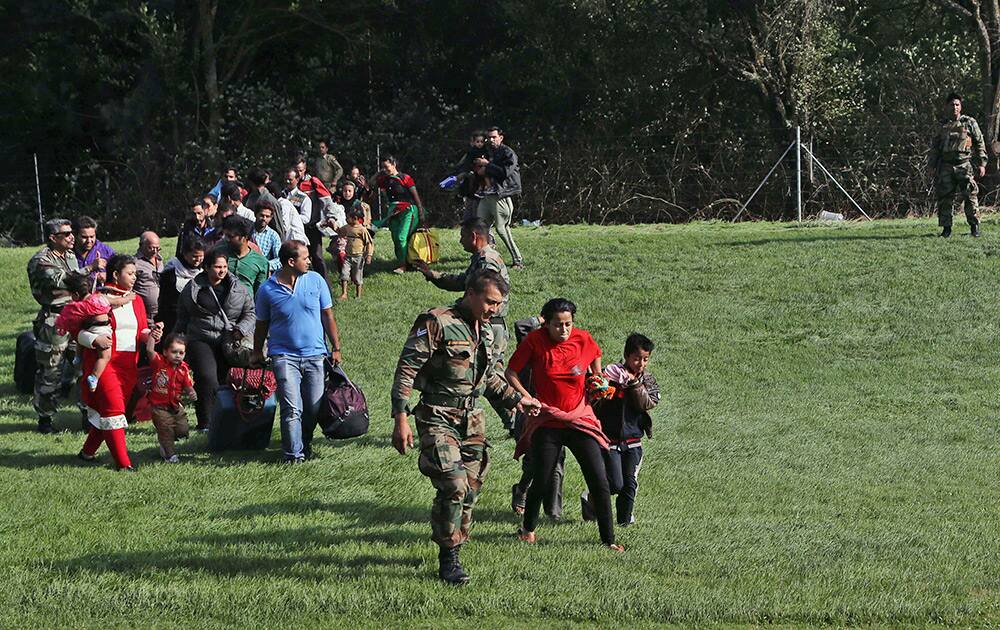 Tourists rescued from flooded areas walk with their children to board a waiting Indian air force helicopter in Srinagar.