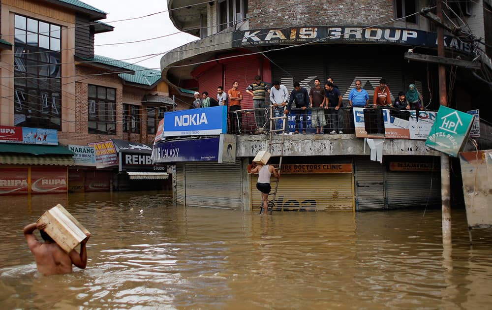 Kashmiri volunteers wade through floodwaters to deliver relief material to victims waiting at a shopping complex in the city center of Srinagar.