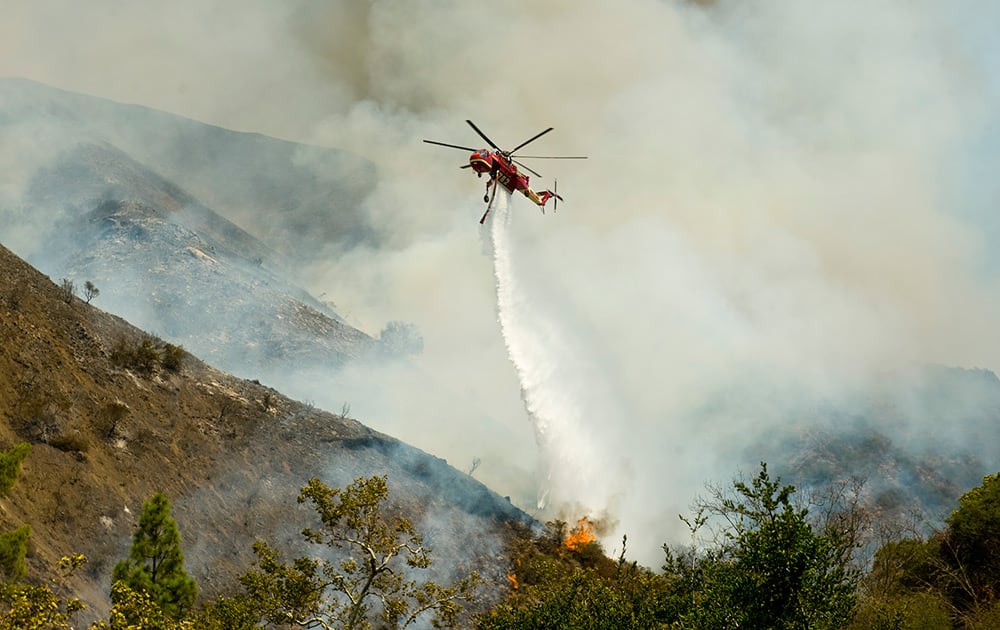 An Orange County Fire Authority helicopter drops a load of water on a brush fire in Silverado Canyon in Orange County, Calif.