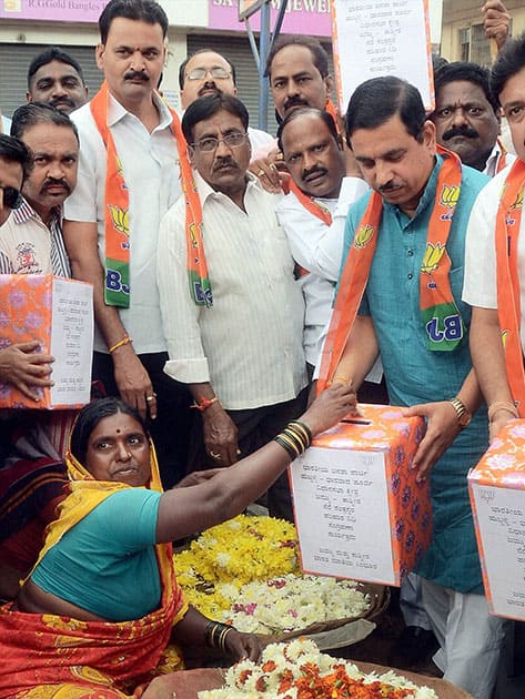 A flower vendor donates money in a box held by BJP Karnataka state President Pralhad Joshi for the Jammu and Kashmir flood relief program in Hubli, Karnatka.