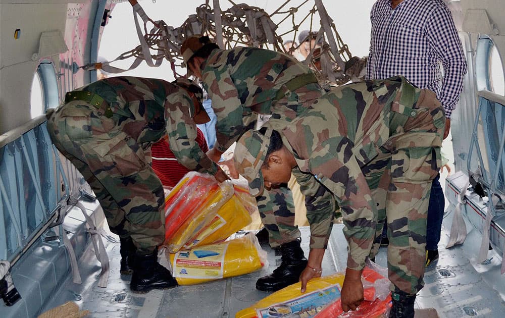 Army soldiers load relief material for the flood victims in remote areas in a helicopter at Rajouri.