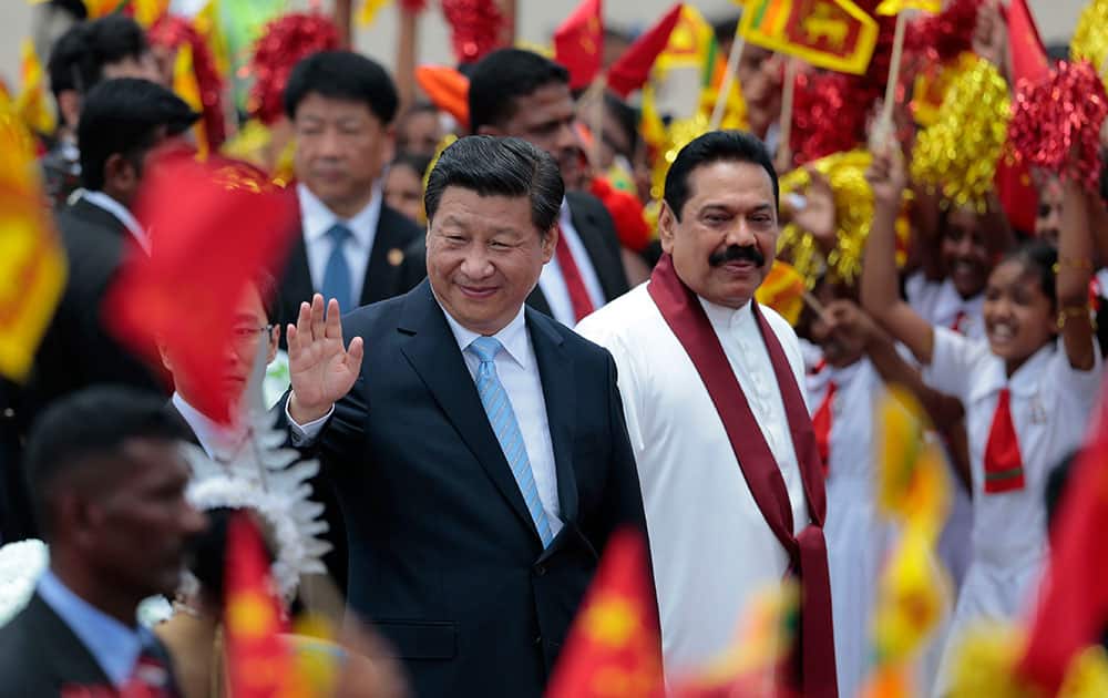 China's President Xi Jinping, left, waves to the gathering as he walks with Sri Lankan President Mahinda Rajapaksa upon arrival at the airport in Colombo, Sri Lanka.