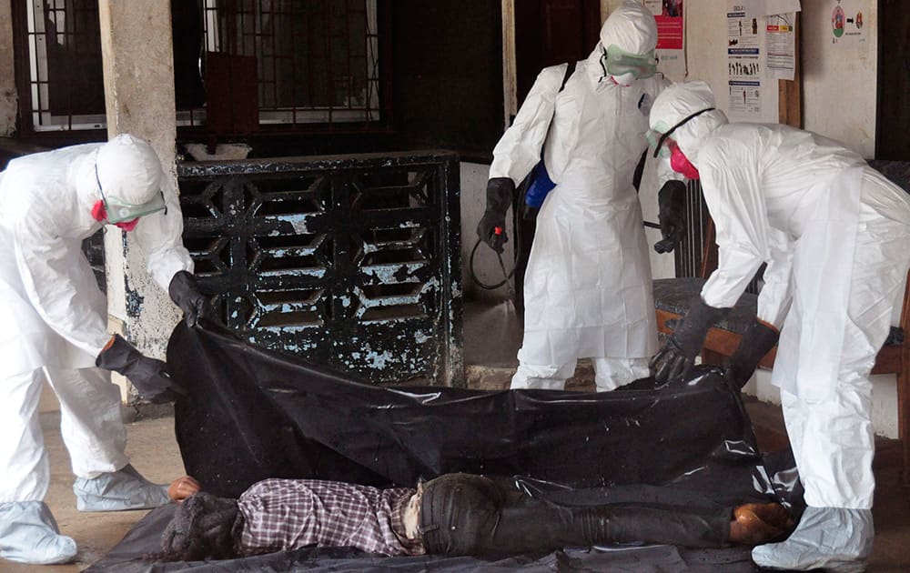 Health workers in protective gear move the body of a person that they suspect died form the Ebola virus in Monrovia, Liberia.