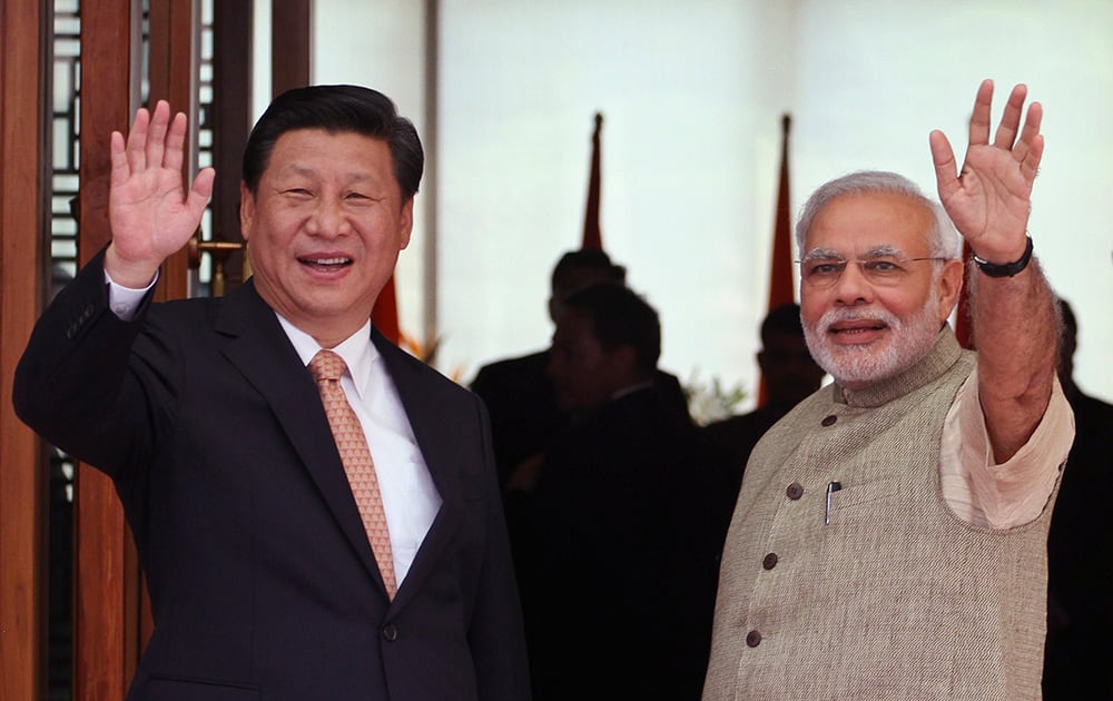 Prime Minister Narendra Modi and Chinese President Xi Jinping wave to the media after Modi received them upon arrival at a hotel in Ahmadabad.