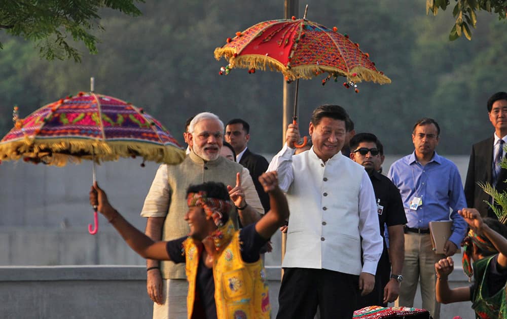 Chinese President Xi Jinping holding umbrella and Indian Prime Minister Narendra Modi watch a cultural performance as they walk on the Sabarmati River front in Ahmadabad.