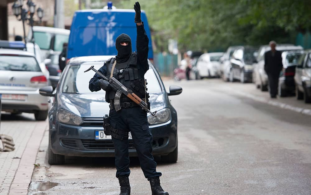 A Kosovo police officer gestures outside the apartment of the vice-president of the radical Islamic political party (LISBA) Fuad Ramiqi, during a police raid, in Pristina.