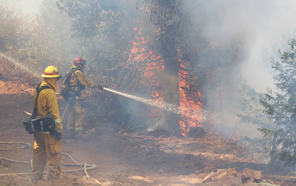 A firefighter hoses down flames from the King fire near Fresh Pond, Calif.