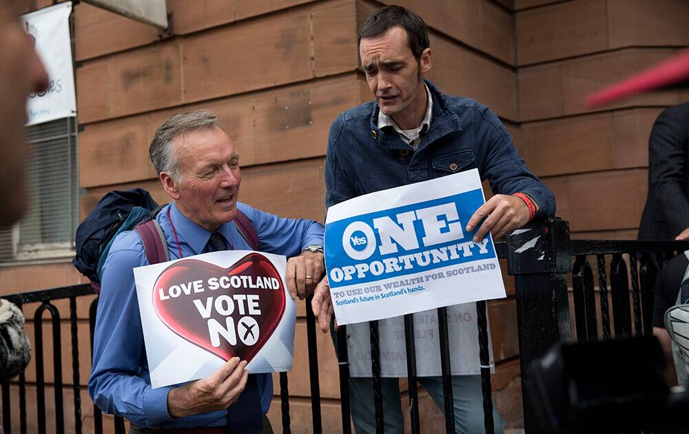 A 'No' campaign supporter and a 'Yes' campaign supporter chat holding posters after a No campaign event where a number of speeches were made by different people and politicians in Glasgow, Scotland.