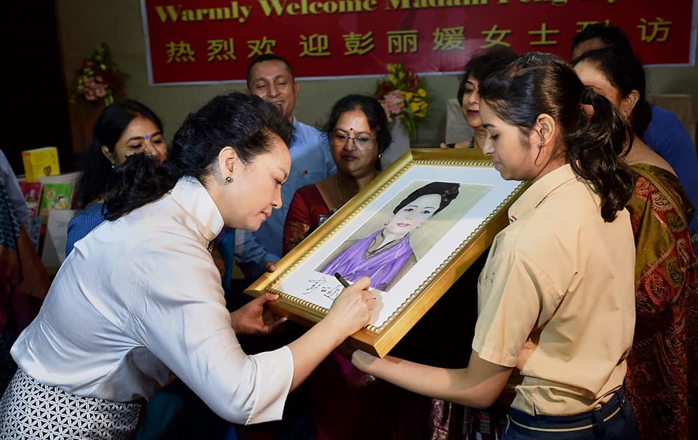 Chinas first lady Peng Liyuan signs on a portrait of her created by a student during a visit to the Tagore International School in New Delhi.