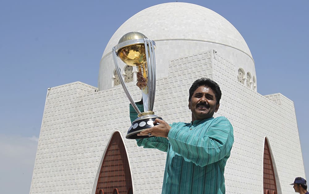 Former Pakistani cricket player Javed Miandad holds the cricket World Cup 2015 trophy in front of the monument of Mohammad Ali Jinnah, in Karachi, Pakistan