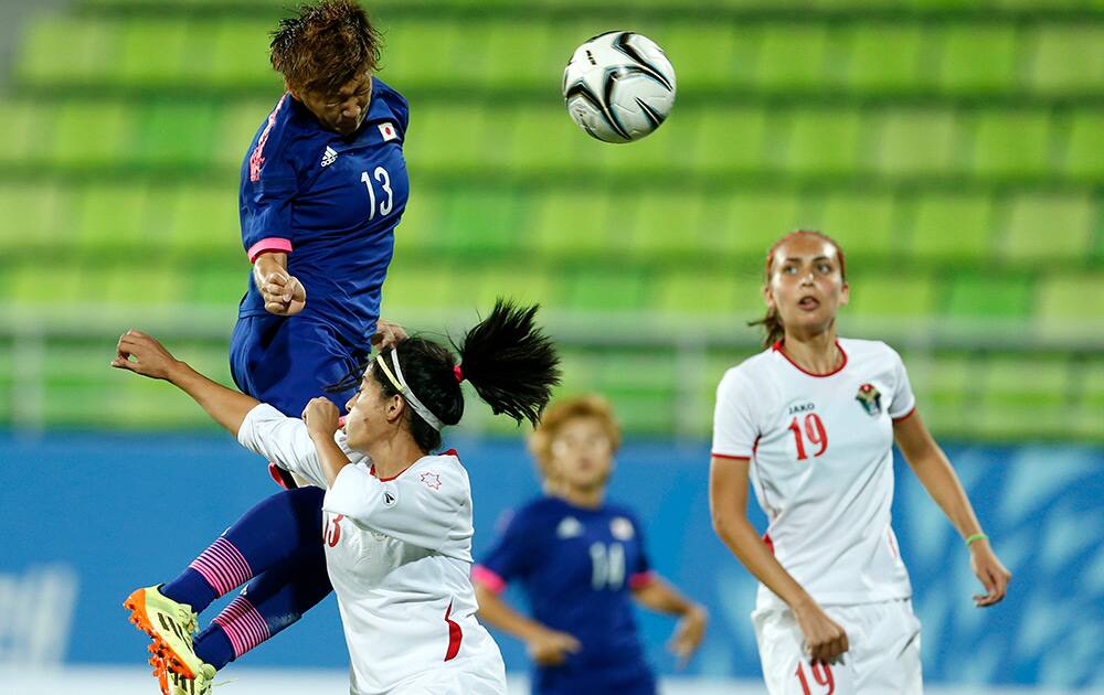 Japan's Yuika Sugasawa leaps over Jordan's Alaa Fouad Daowd Abu Kasheh to score a goal as Ayah Faisal Ayed Al Majali, looks on during their match at the 17th Asian Games in Incheon, South Korea.