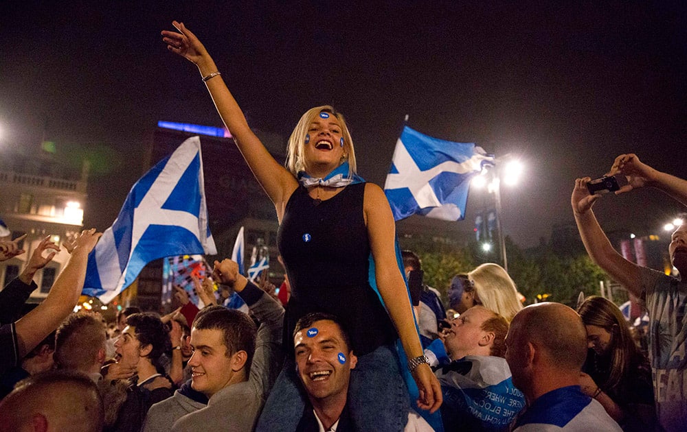 A man carries a woman on his shoulders as supporters of the Yes campaign in the Scottish independence referendum shout and cheer as they await the result after the polls closed, in George Square, Glasgow, Scotland.