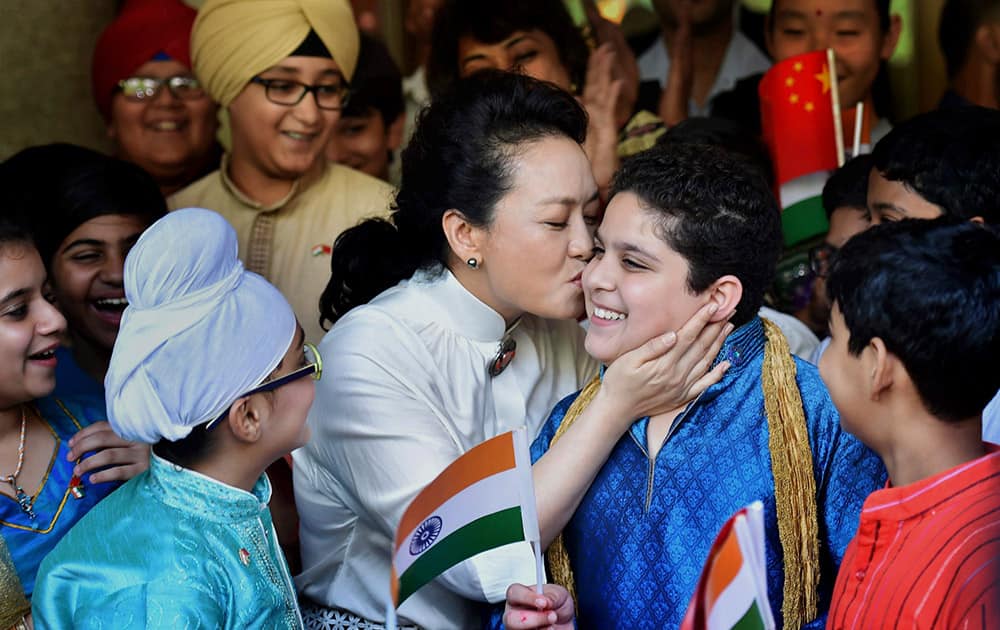 Visiting Chinese President Xi Jinping’s wife Peng Liyuan kisses a student during a visit to the Tagore International School in New Delhi.