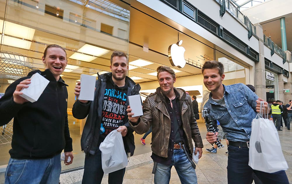 Customers smile with new mobile phones in their hands during the launch of the Apple iPhone 6 sale at a store in Oberhausen, Germany.