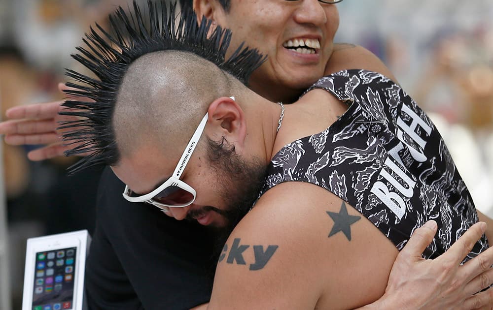 Ken Miyauchi, left, vice president of Softbank, Japanese mobile phone company hugs the first customer of iPhone 6 during a ceremony to mark the first day of sales of the new Apple iPhone 6 and 6 Plus at a store in Tokyo.