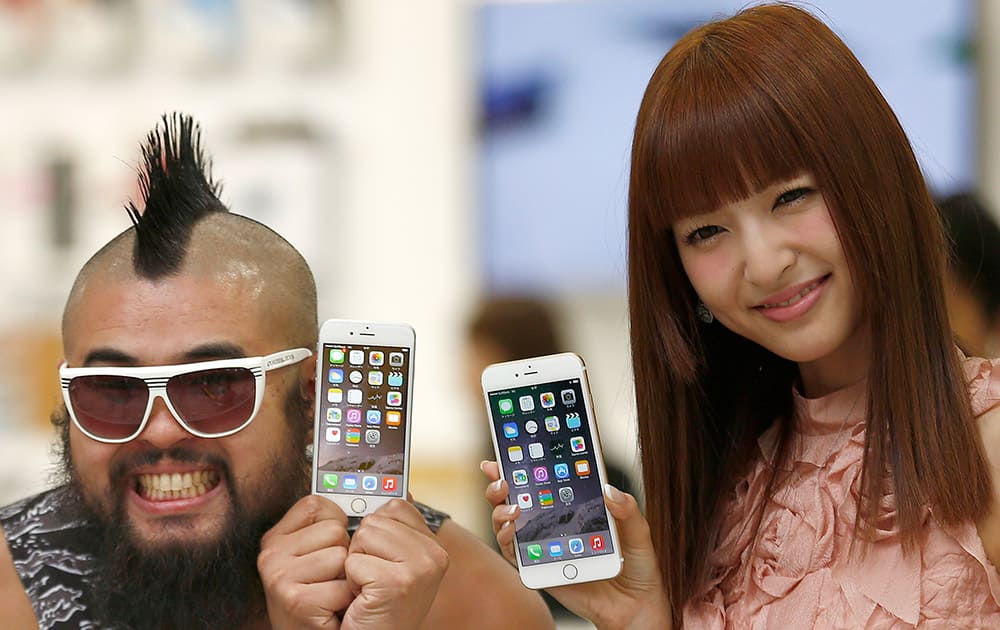 A customer and actress Sayaka Kanda pose for photographers during a ceremony to mark the first day of sales of the latest iPhone 6 and 6 Plus at a store in Tokyo .