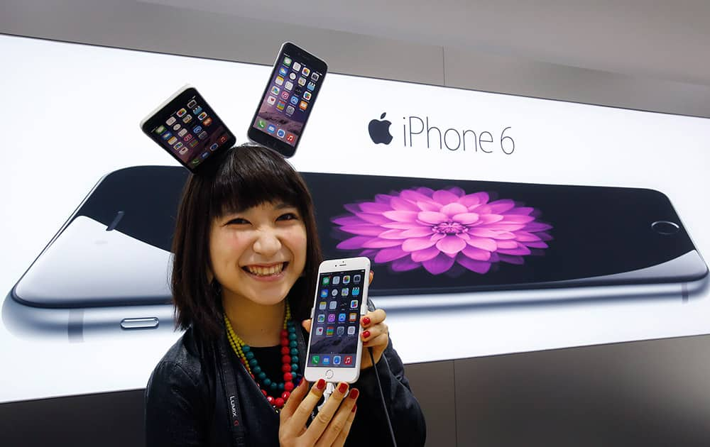 A customer poses for photographers during a ceremony to mark the first day of sales of the new Apple iPhone 6 and 6 Plus at a store in Tokyo.