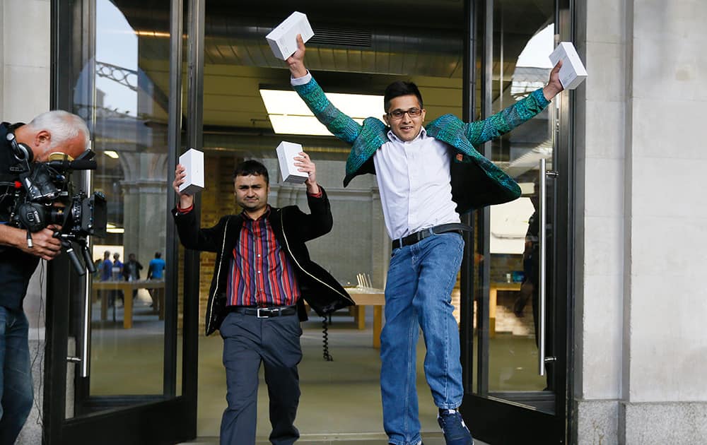 The first people in the queue, Sam Sheikh, left, and Jameel Ahmed, right, celebrate for the media after buying the new iPhone6, outside the Apple shop in London.