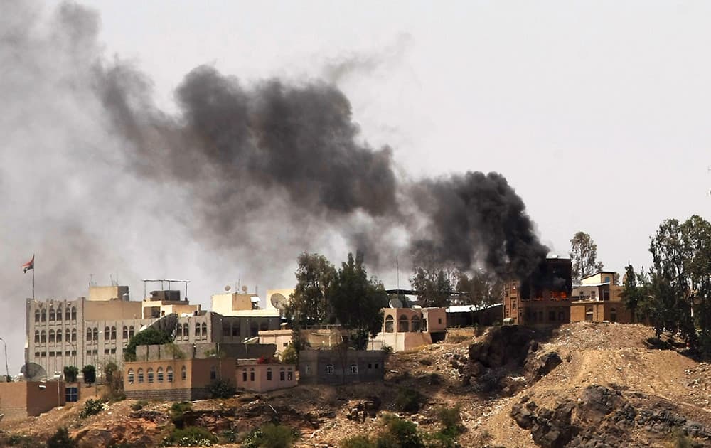 Smokes rises from near the Yemeni Government TV building, background, during clashes between Sunni militiamen and Hawthi Shiite rebels in Sanaa, Yemen.