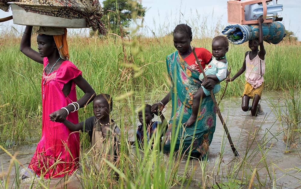 A family of the Nuer ethnic group seeking medication and food, but who were planning to later return to their village in a Nuer rebel-controlled area, walk through flooded areas to reach a makeshift camp for the displaced situated in the United Nations Mission in South Sudan (UNMISS) base in the town of Bentiu, South Sudan.
