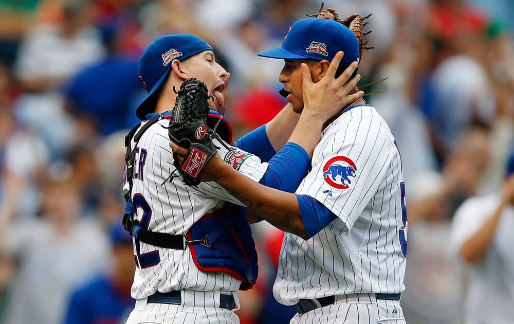 Chicago Cubs catcher John Baker, left, and relief pitcher Hector Rondon, right, celebrate after defeating the Los Angeles Dodgers in a baseball game.