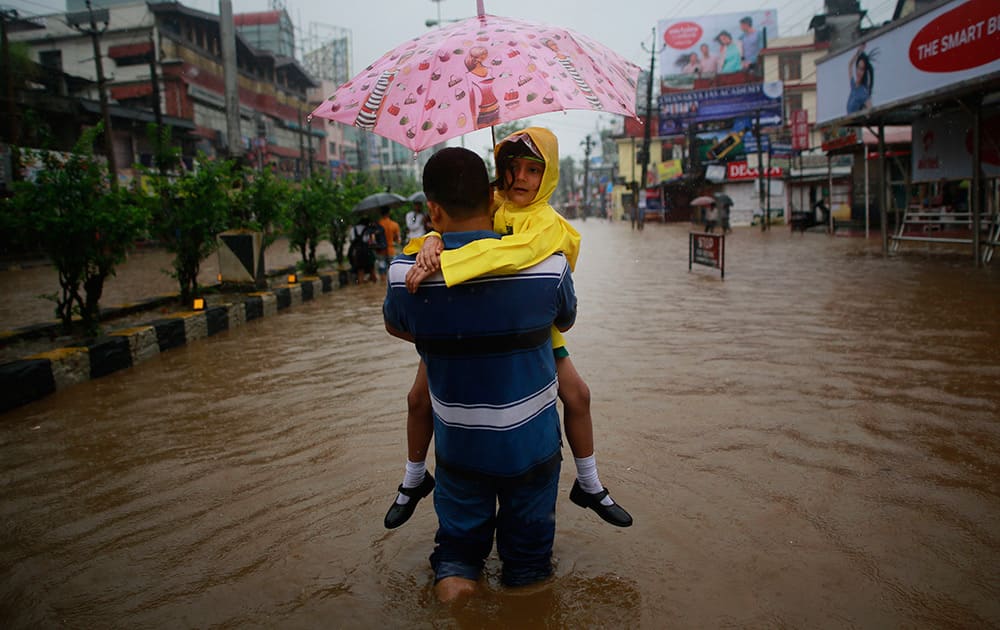 A man carrying his daughter wades through floodwaters in Guwahati, Assam. Officials say relentless rains in parts of northeastern India have triggered landslides and flash floods, killing at least seven people.