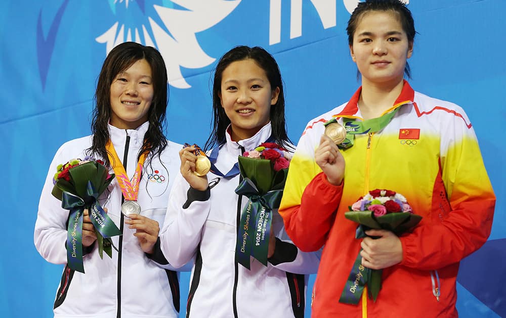 Japan's Kanako Watanabe, centre, stands on the podium after winning the gold medal in the women's 200-meter breaststroke swimming final with compatriot and silver medalist Rie Kaneto, left, and China's bronze medalist Shi Jinglin, right, at the 17th Asian Games in Incheon, South Korea.