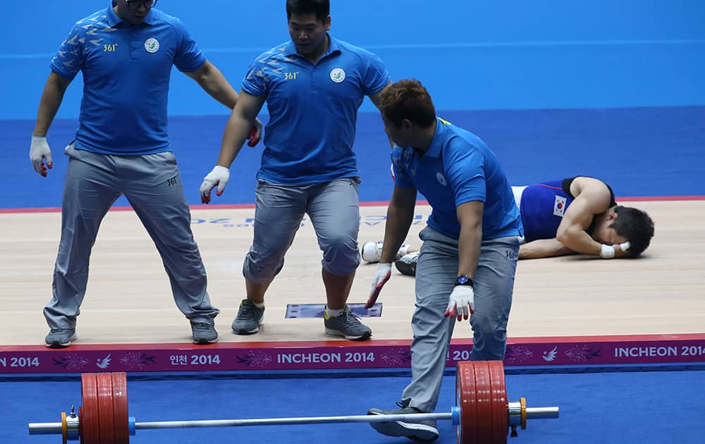 Competition officials rush to remove the barbell as South Korea's Won Jeong-sik suffers an injury during the men's 69kg weightlifting competition at the 17th Asian Games in Incheon, Korea.