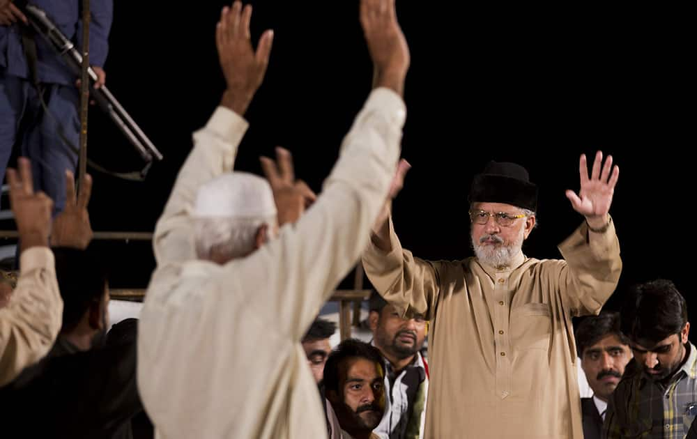 Pakistan's fiery Muslim cleric Tahir-ul-Qadri, left, greets his supporters, camped in the vicinity of the parliament building in Islamabad, Pakistan.