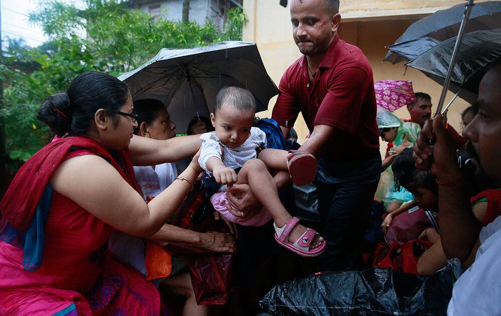 A rescuer hands over a child to a mother in a boat after heavy monsoon rains flooded parts of Gauhati, Assam state, India.