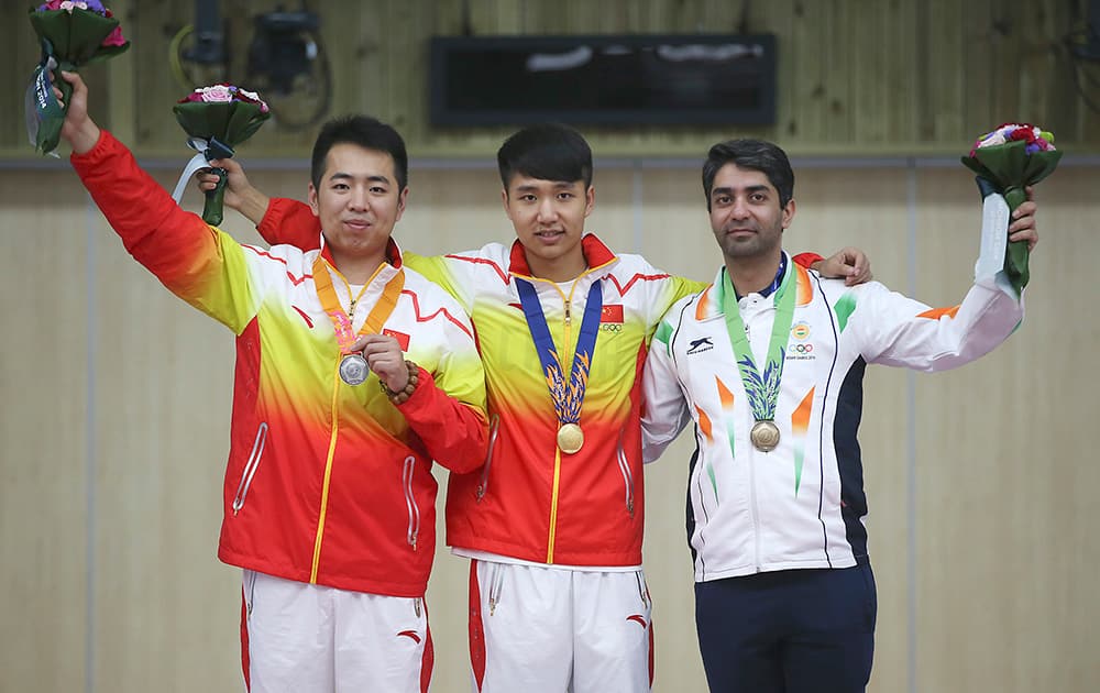 Silver medalist Cao Yifei, left, of China, gold medalist Yang Haoran, center, of China and bronze medalist Abhinav Bindra, right, of India pose for photographers during the victory ceremony for the men's 10m air rifle individual competition at the 17th Asian Games.