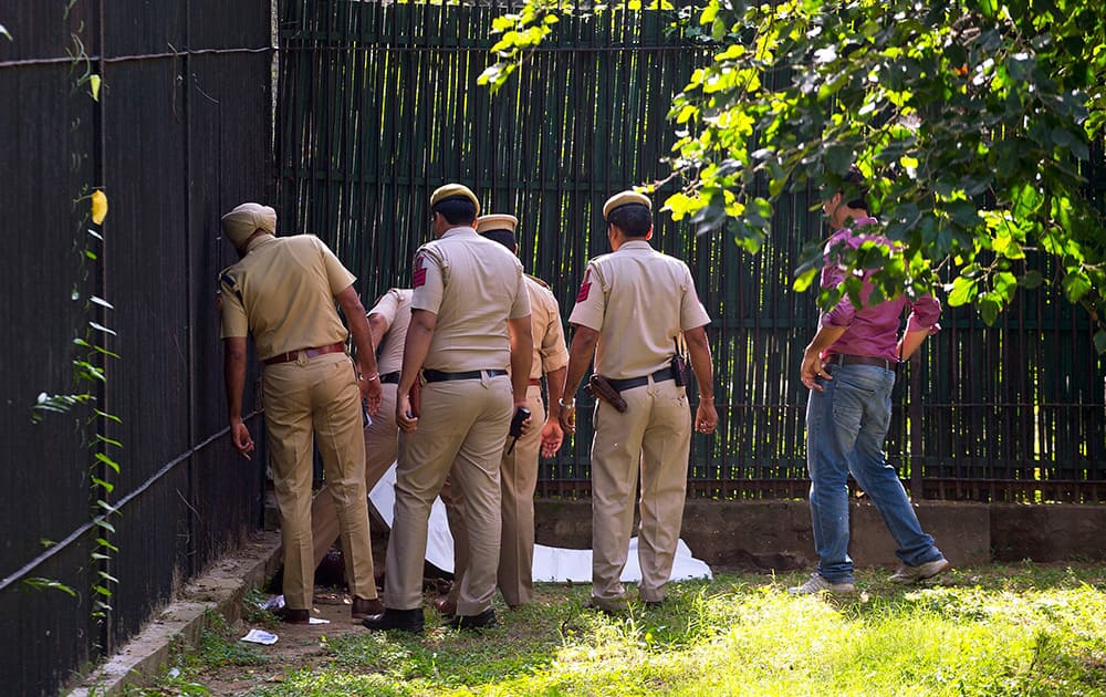 Policemen inspect the body of a man who was killed by a white tiger at the zoo in New Delhi.