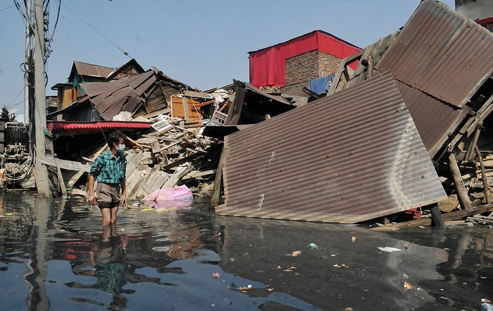 A man looks at the damaged houses in a flood hit area on the outskirt of Srinagar.