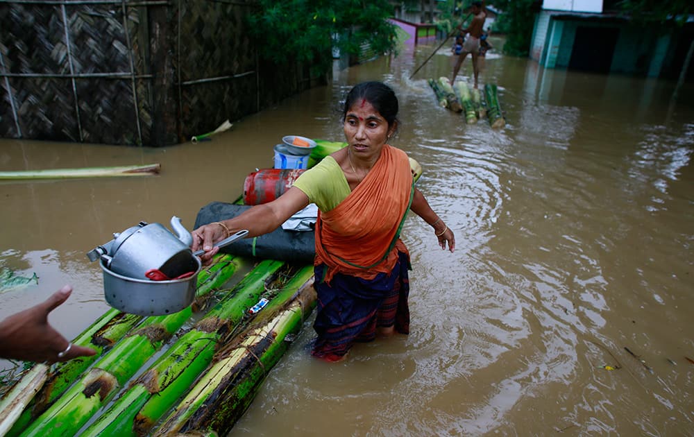 A flood affected woman tries to salvage her belongings on a banana raft at the Chaygaon village in Kamrup district of northeastern Assam.