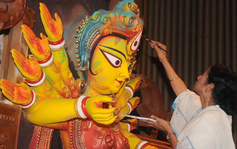 West Bengal Chief Minister Mamata Banerjee gives final touches to eyes of an idol of Goddess Durga in Kolkata.