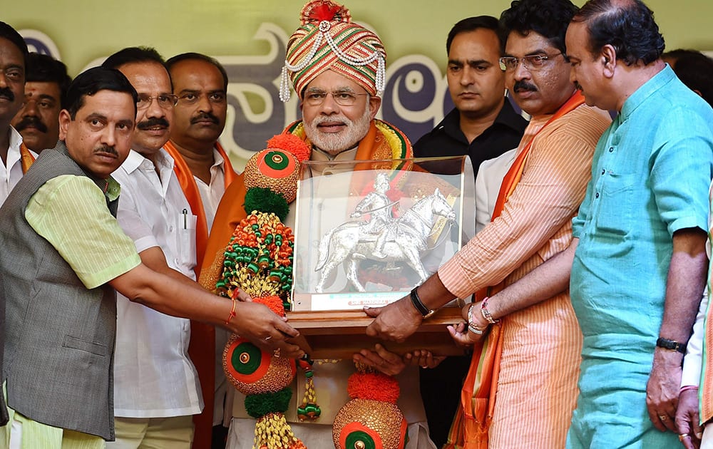 Prime Minister Narendra Modi being handed over a memento by state BJP leaders at a rally outside the HAL Airport in Bengaluru.